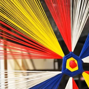Close-up of colorful dyed yarn strands converging at a central spool core
