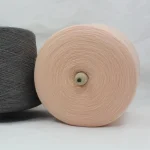 2/45 merino wool blend yarn cone in pale pink front view with dark gray cone beside it