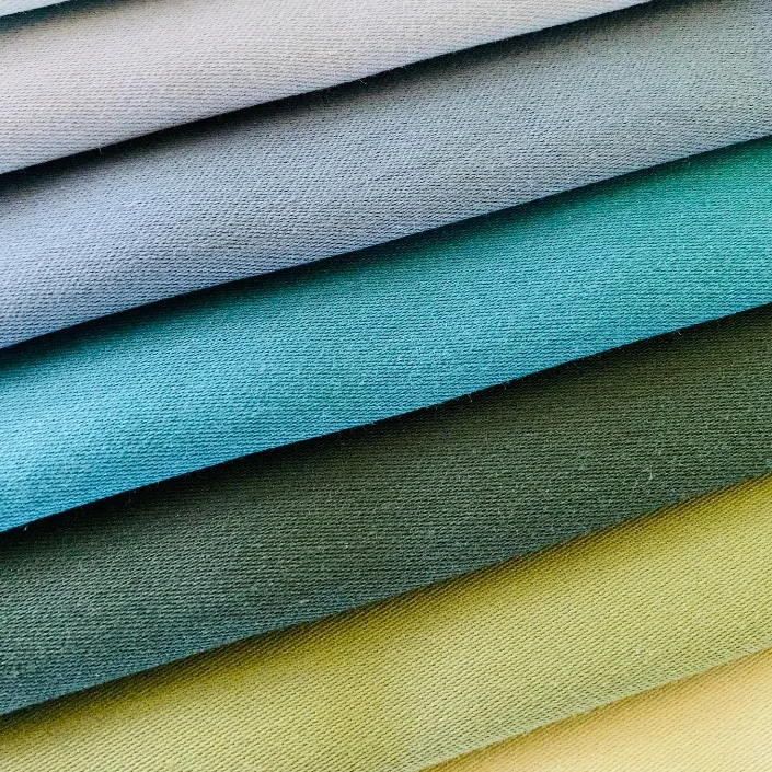 Layered knitted fabric samples in different colors showing texture, softness, and functional textile application potential
