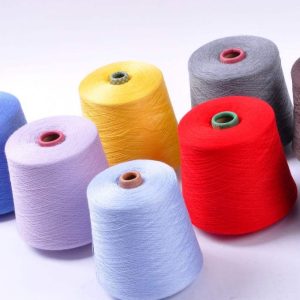 Colored yarn cones on a white background in red, yellow, gray, lavender, and light blue.