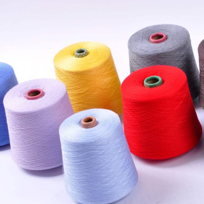 Colored yarn cones on a white background in red, yellow, gray, lavender, and light blue.